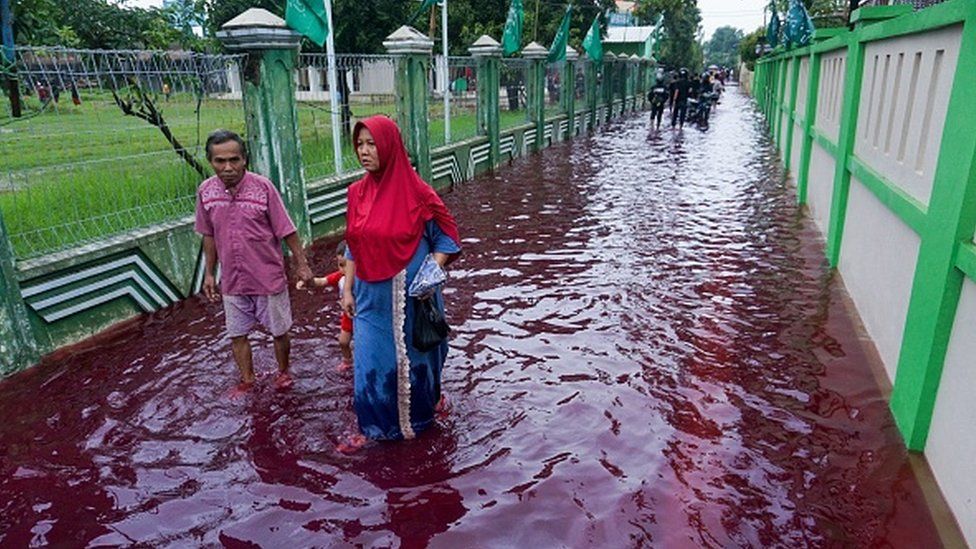 Blood-red floodwaters gush through Indonesian village